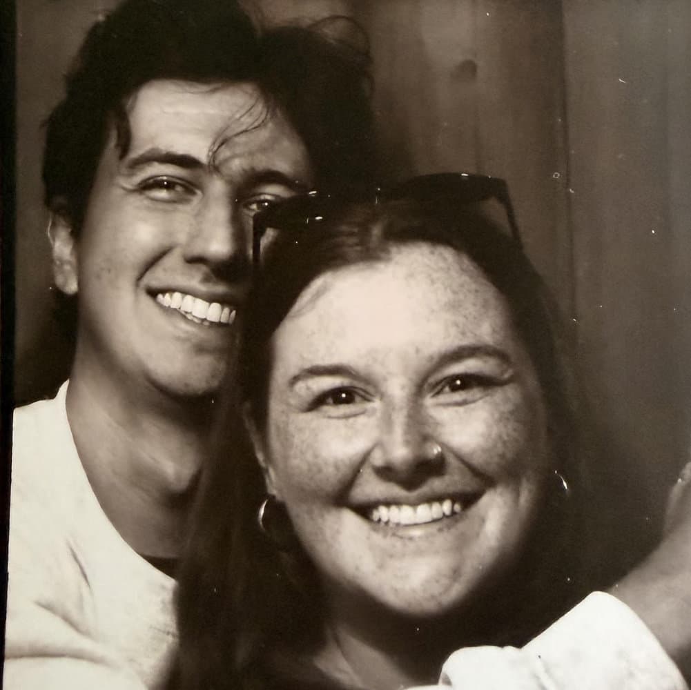 Devin and Megan smiling together in a black-and-white photo booth picture